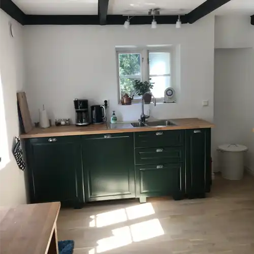 del av mörkgrönt kök med arbetsbänk och mörka bjälkar i taket